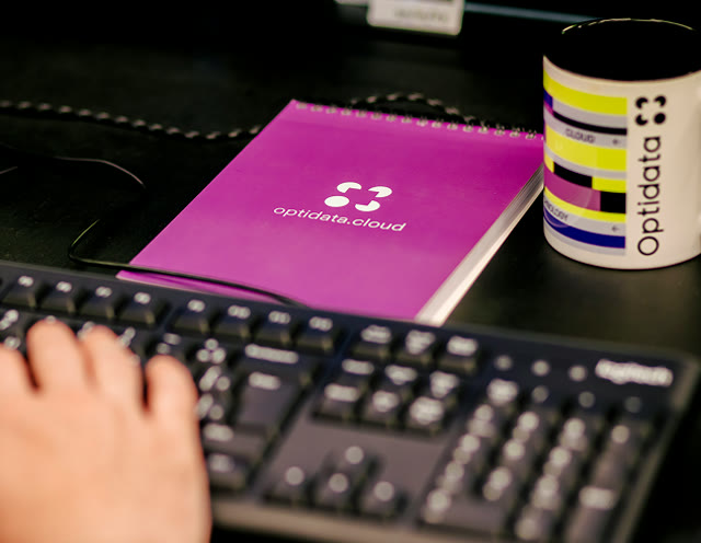 Optidata Cloud notebook and branded mug on a desk